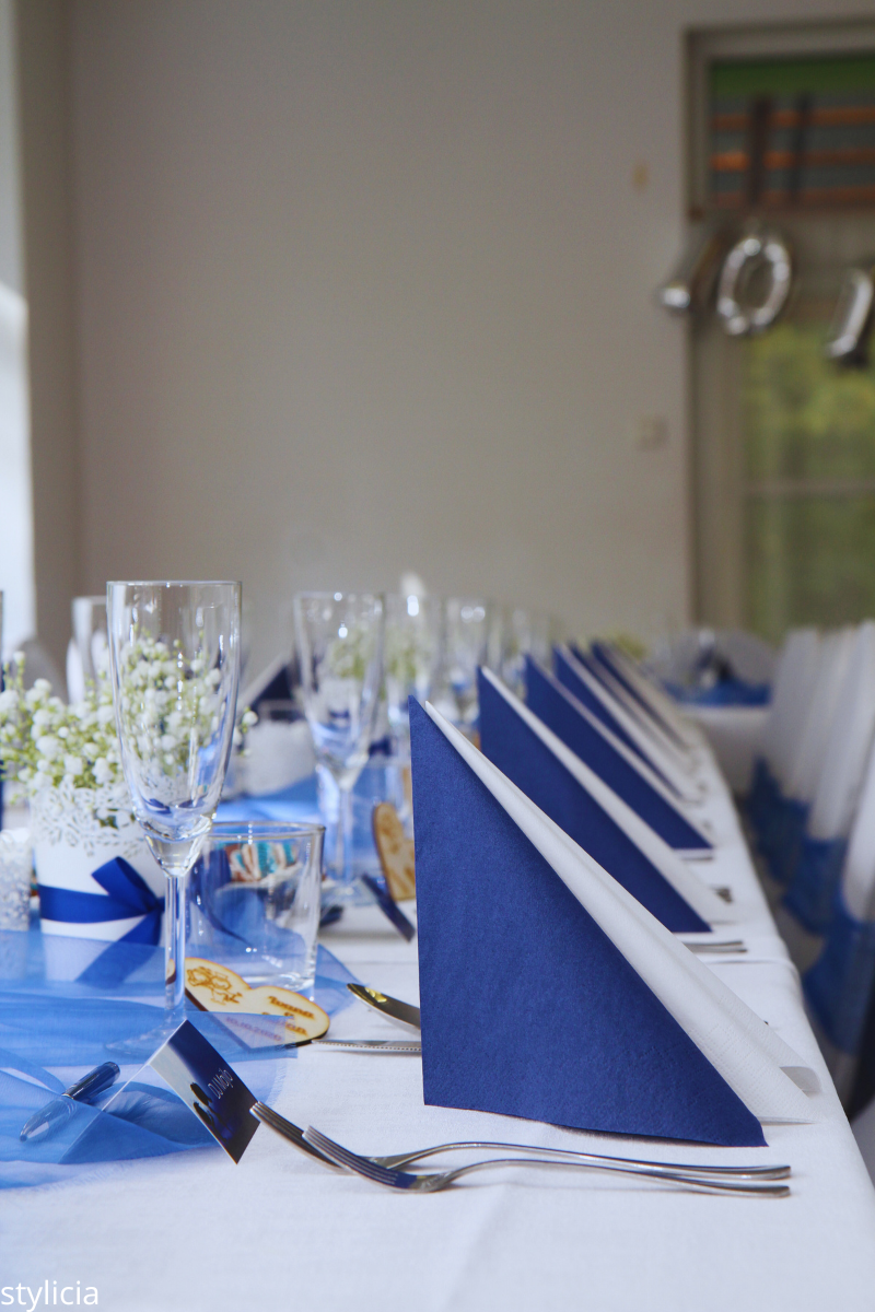 Elegant wedding table setting with navy blue napkins, glassware, and white details, highlighting a classic wedding color combination.