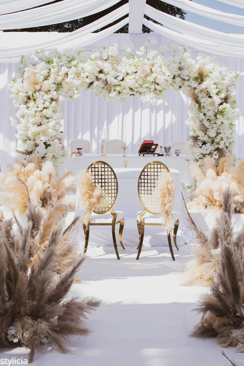 Elegant wedding arch with white florals and pampas grass, showcasing soft neutrals and earthy accents as a timeless wedding color trend.