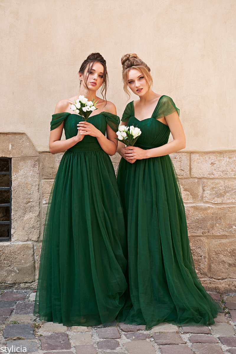 Bridesmaids in deep emerald green dresses holding white flowers, showcasing jewel tone wedding color trends for a bold and romantic look.