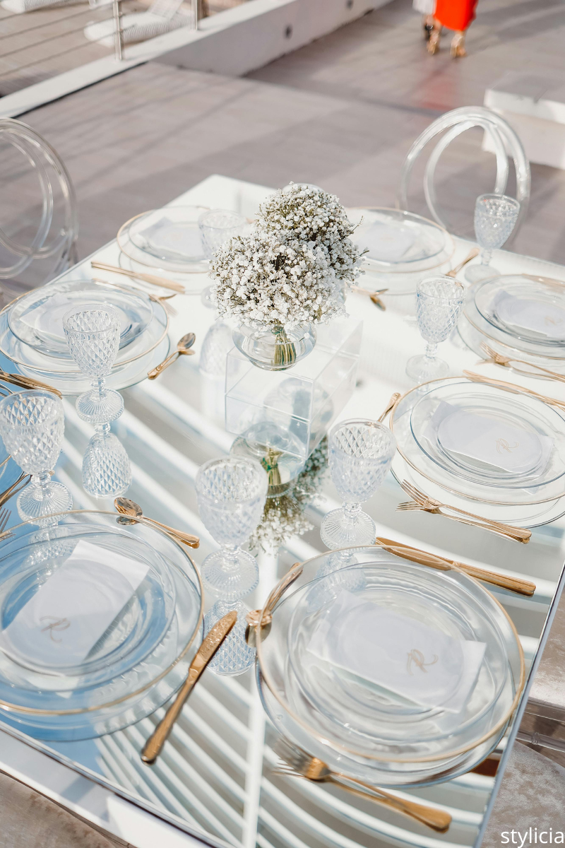 Elegant wedding table setting with glass plates, gold cutlery and baby’s breath centerpiece – example of things wedding guests don’t care about in detail.