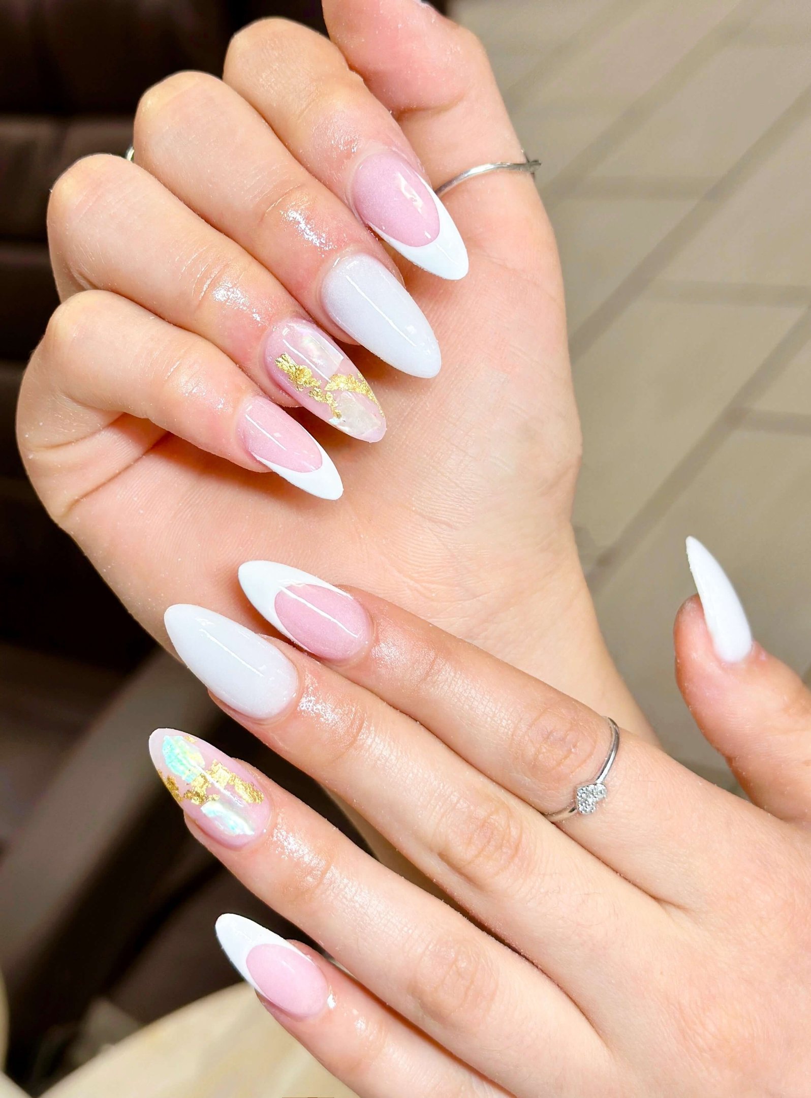 Summer nail trend with elegant almond-shaped nails featuring white French tips, soft pink accents, and iridescent nail art with gold foil details.