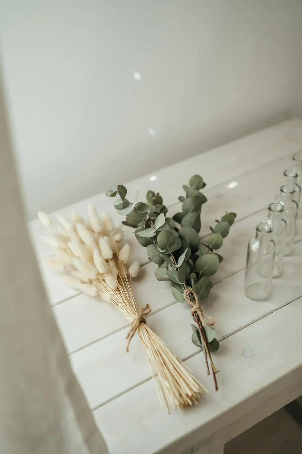 Fall wedding flowers you can buy early: bunches of dried bunny tail grass and preserved eucalyptus tied with twine