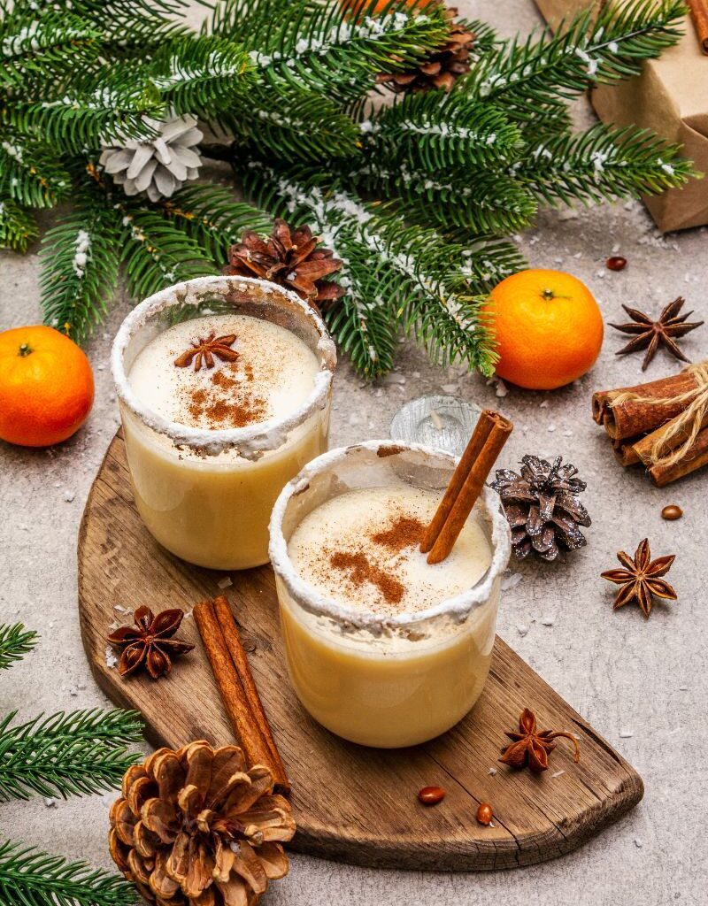 Creamy homemade eggnog in sugar-rimmed glasses, topped with cinnamon and star anise in a festive Christmas setting.