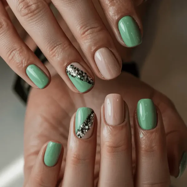 Short square early fall nails — mint green and blush pink with diagonal black and silver glitter accent nail