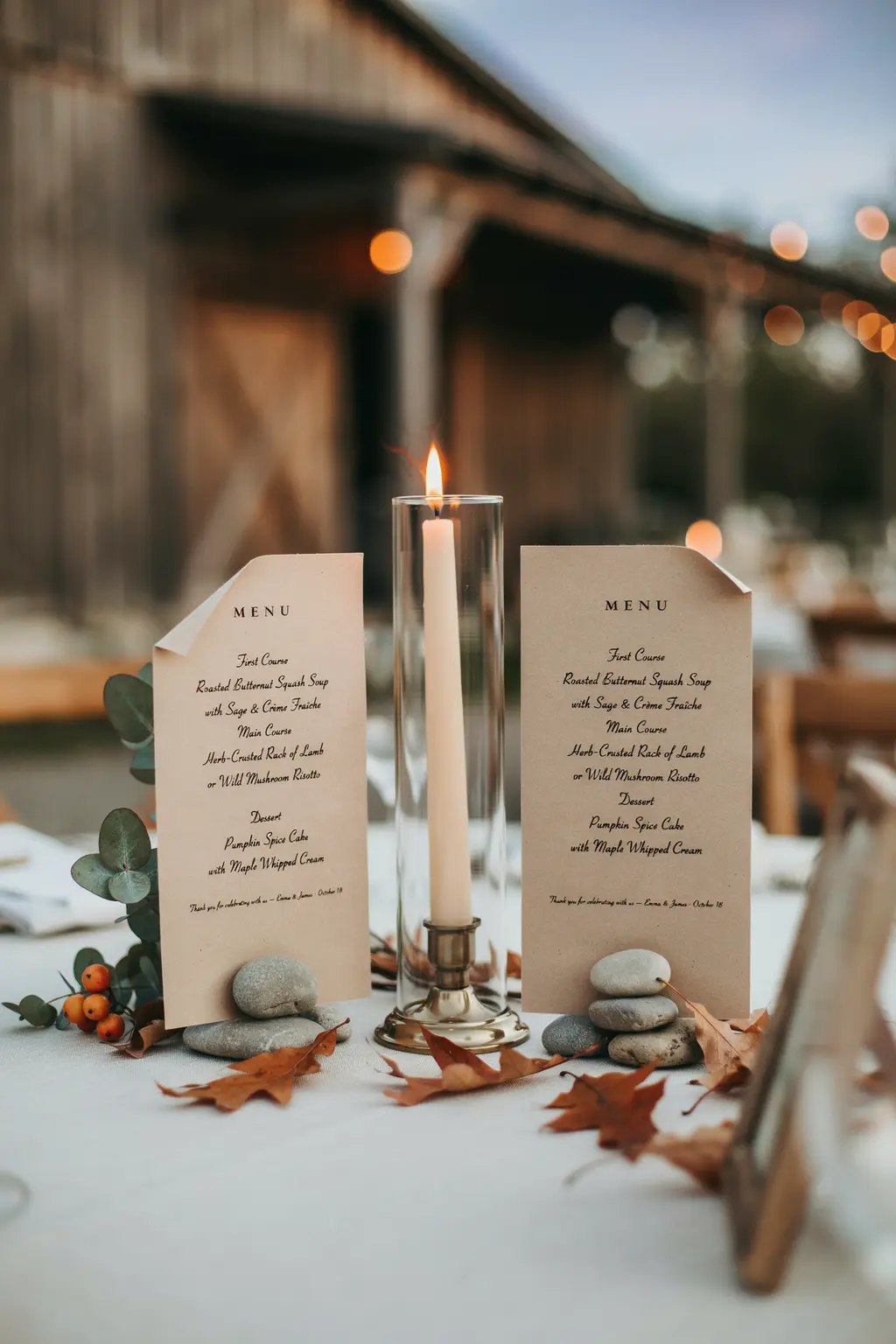 Fall outdoor wedding menu cards weighted with stones and a hurricane shade over the candle in wind