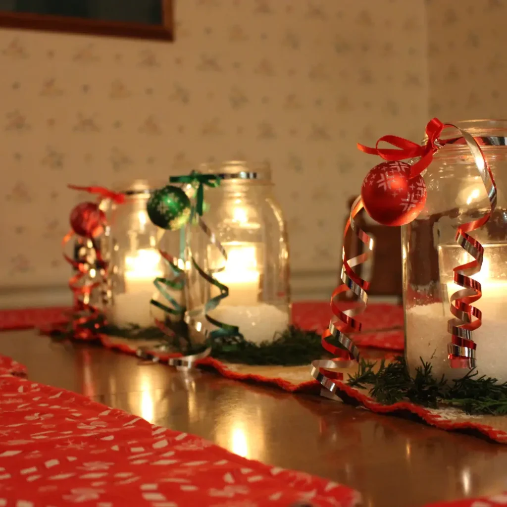 budget-friendly DIY Christmas table decor with mason jar candle lanterns, ribbon ornaments and warm festive lighting