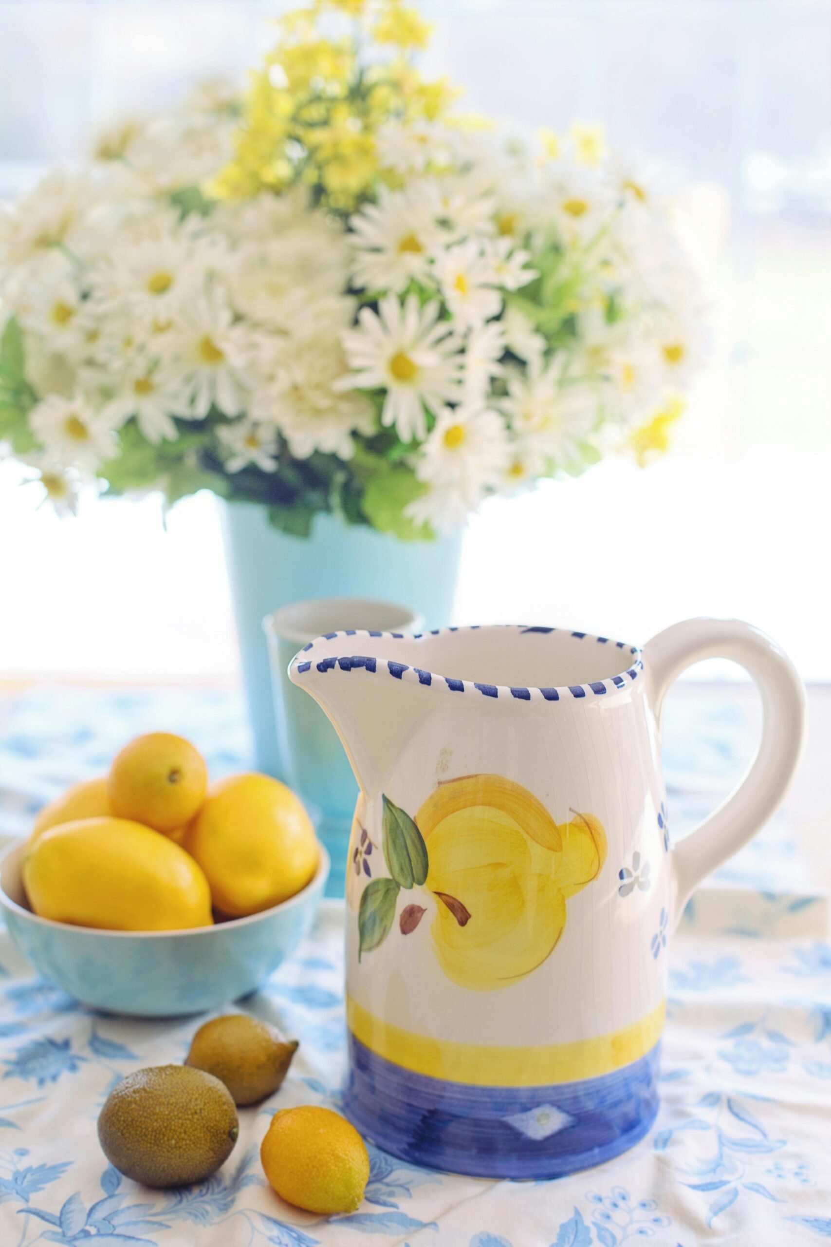 Lemon-themed ceramic pitcher and bowl of lemons with daisy flowers - lemon decor having a moment